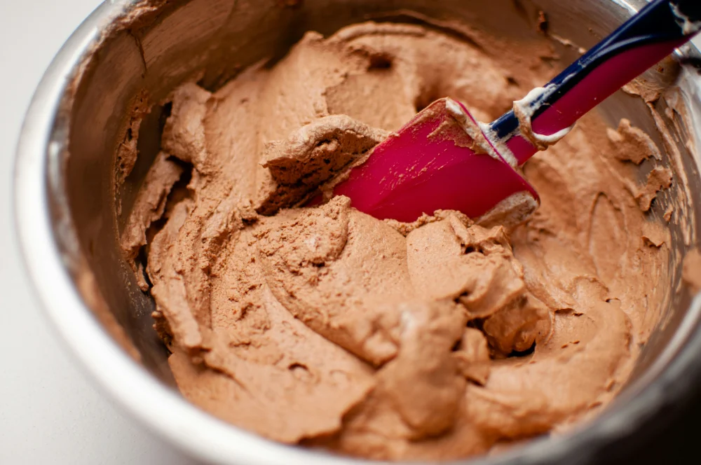 chocolate cake icing in a mixing bowl with a spatula