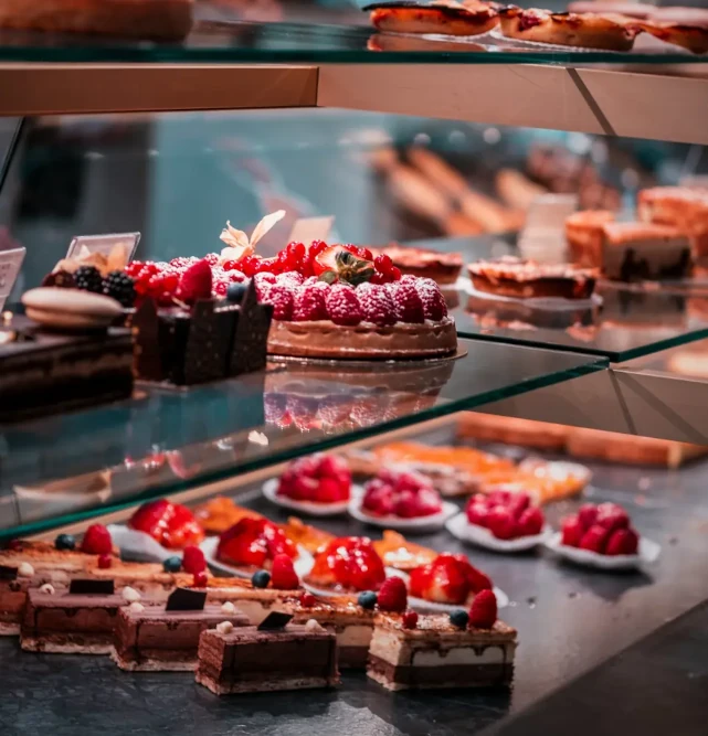 Various small cakes and desserts in a glass cafe cabinet